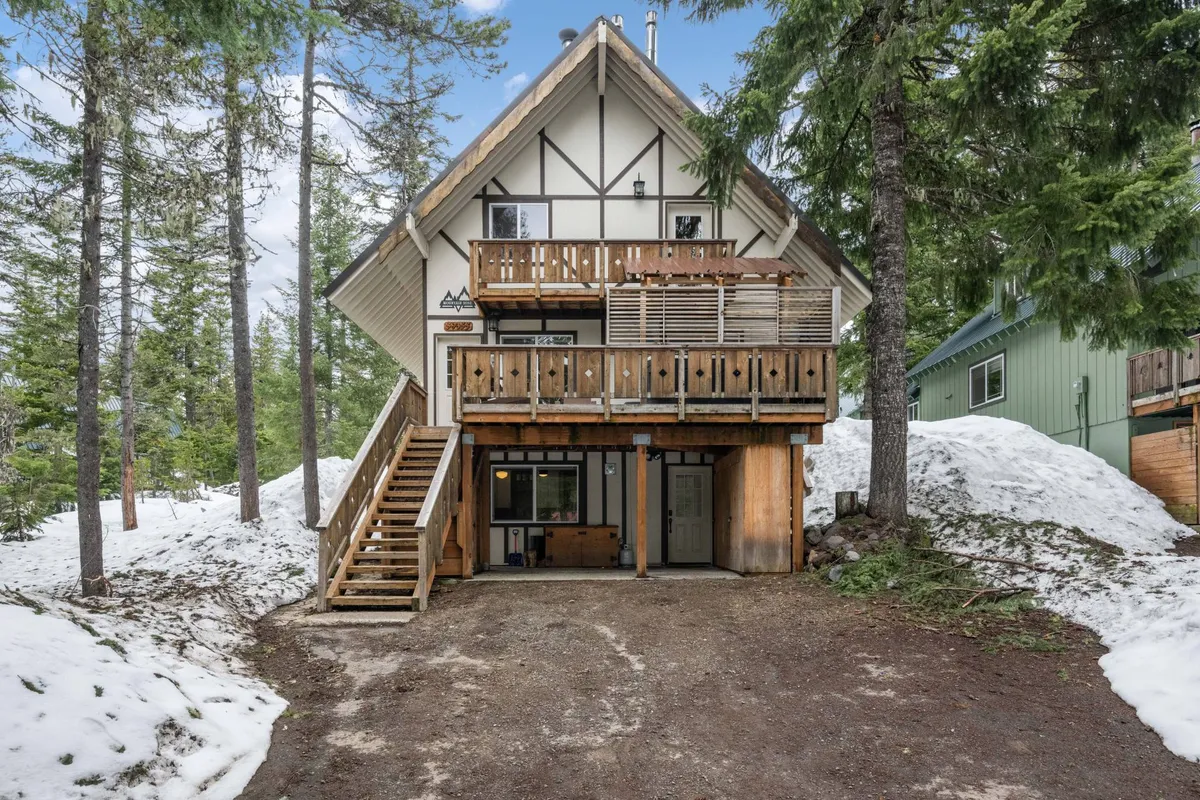 An exterior view of the home’s wooden balcony with a staircase leading up to the entrance, surrounded by trees and nature. The setting suggests immediate outdoor access for both morning walks and pet-friendly activities.