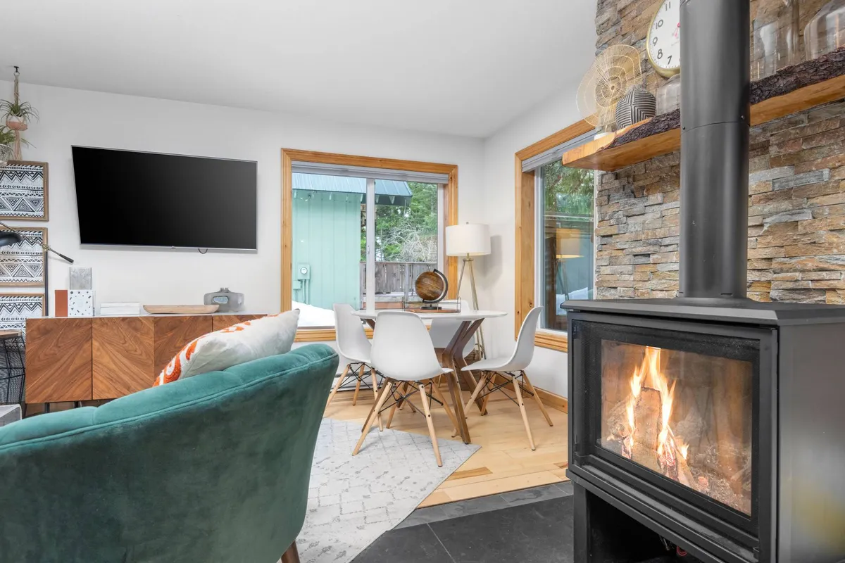 A warm, welcoming interior featuring a fireplace, a dining table, and a plush green chair. The ambiance is cozy, making it a perfect spot to relax after outdoor activities with pets or gather for meals in a peaceful setting.